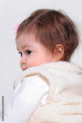 The small beautiful girl lies on a white background with toys