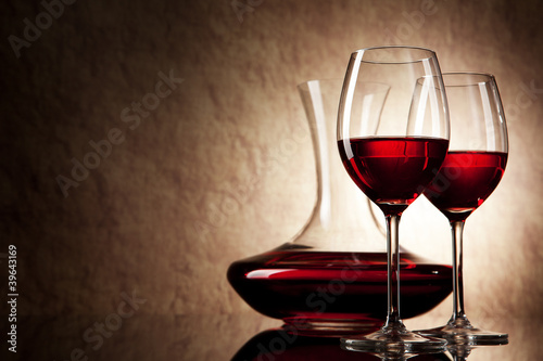 decanter with red wine and glass on a old stone background photo