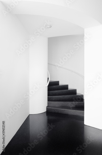 Spiral staircases between white walls and black floor