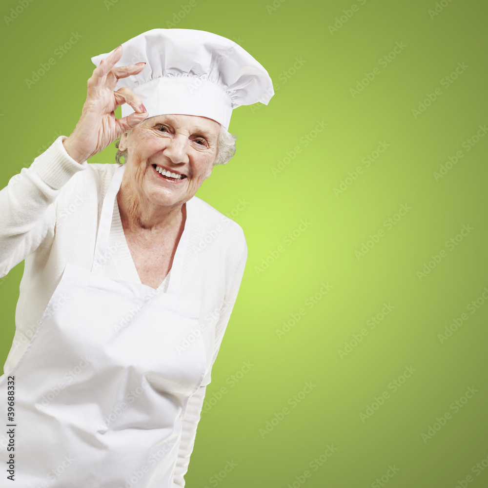 senior woman cook doing an excellent symbol against a green back senior woman cook doing an excellent symbol against a green back