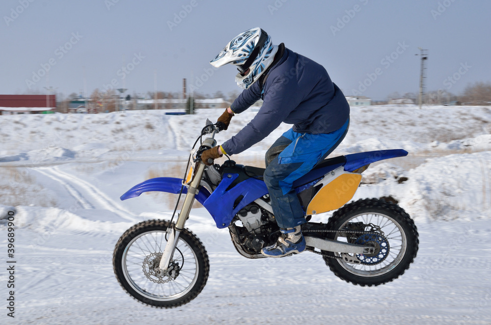 Naklejka premium Motocross, motorcycle driver flies over hill out of snow