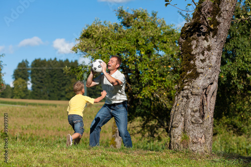 Glückliche Familie spielt Fußball im Sommer