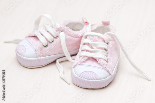 little girlie baby shoes on a wooden floor