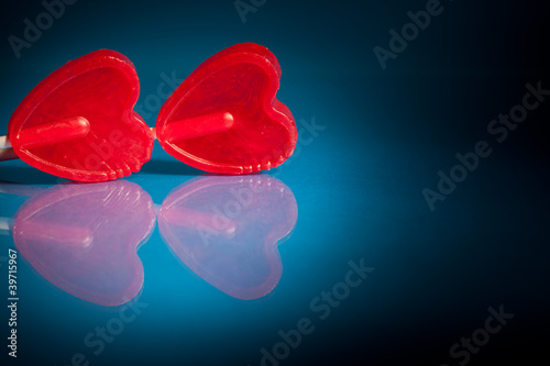 Couple of red heart lollipops on blue background
