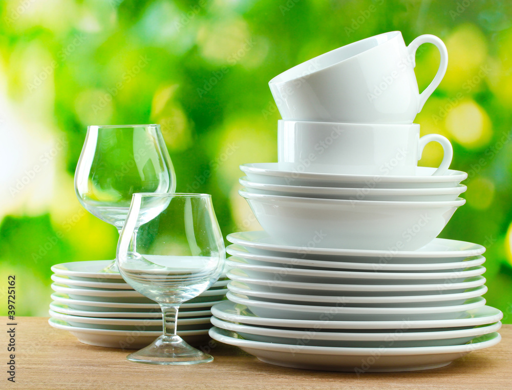 Clean dishes on wooden table on green background Clean dishes on wooden table on green background