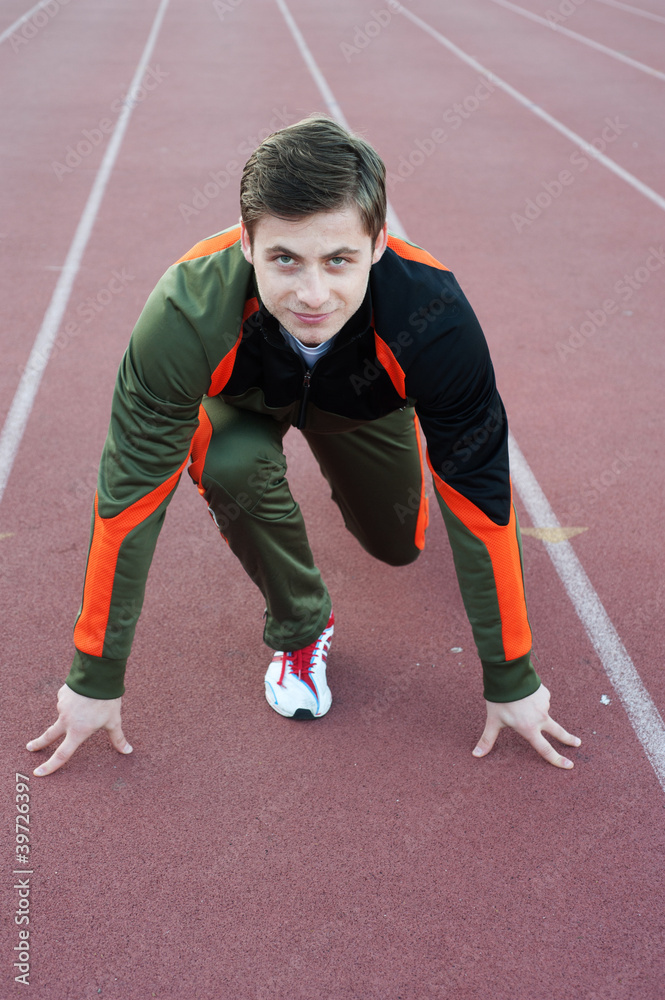 Young male athlete in ready position on running track