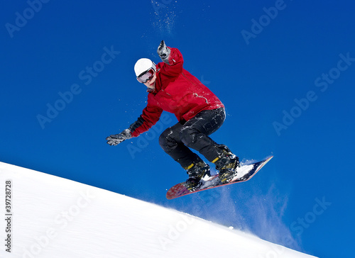 Snowboarder jumping through air with deep blue sky