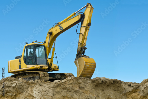 Yellow excavator on sand hill