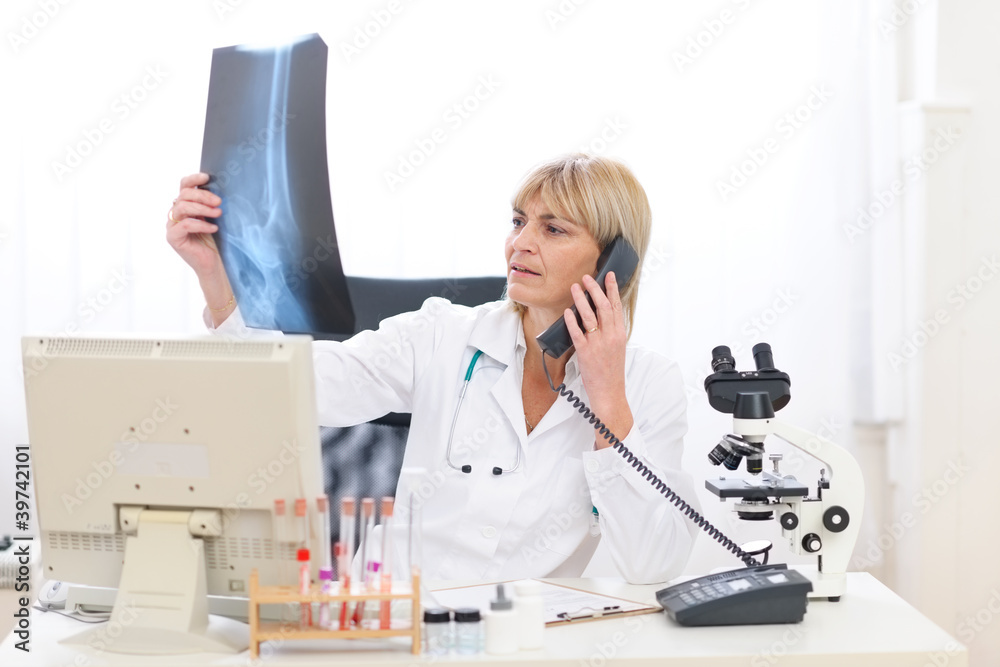 Senior doctor woman speaking phone and looking on roentgen Senior doctor woman speaking phone and looking on roentgen
