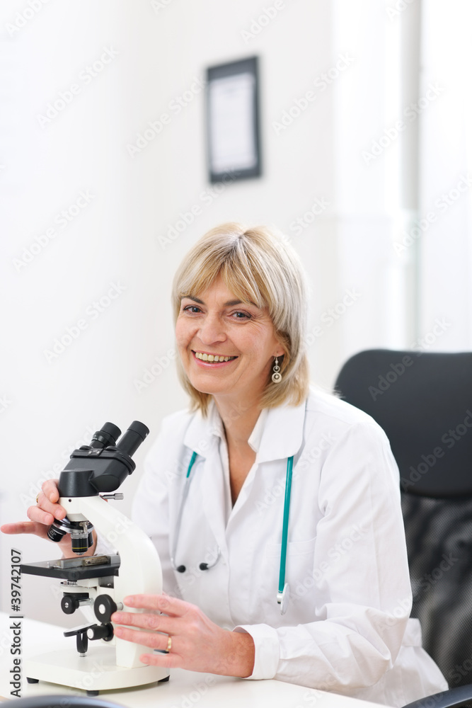 Smiling senior doctor woman working with microscope at lab Smiling senior doctor woman working with microscope at lab