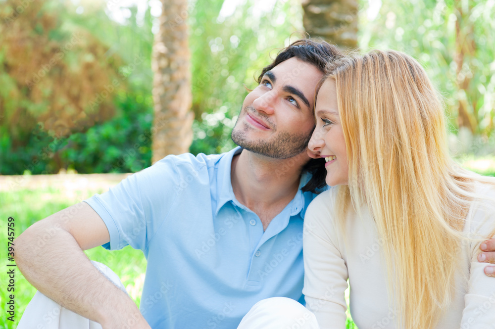 Obraz premium Romantic young couple sitting together in summer park