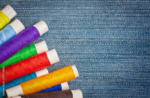 Sewing thread reels on a blue denim background photo