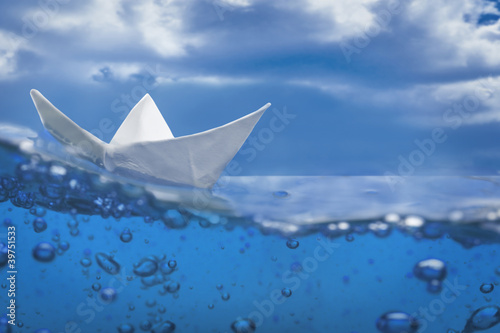 paper ship splash with bubbles sailing in blue water and sky