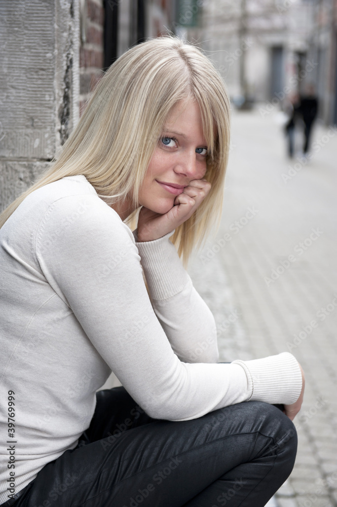 young woman seated outdoors in the city young woman seated outdoors in the city