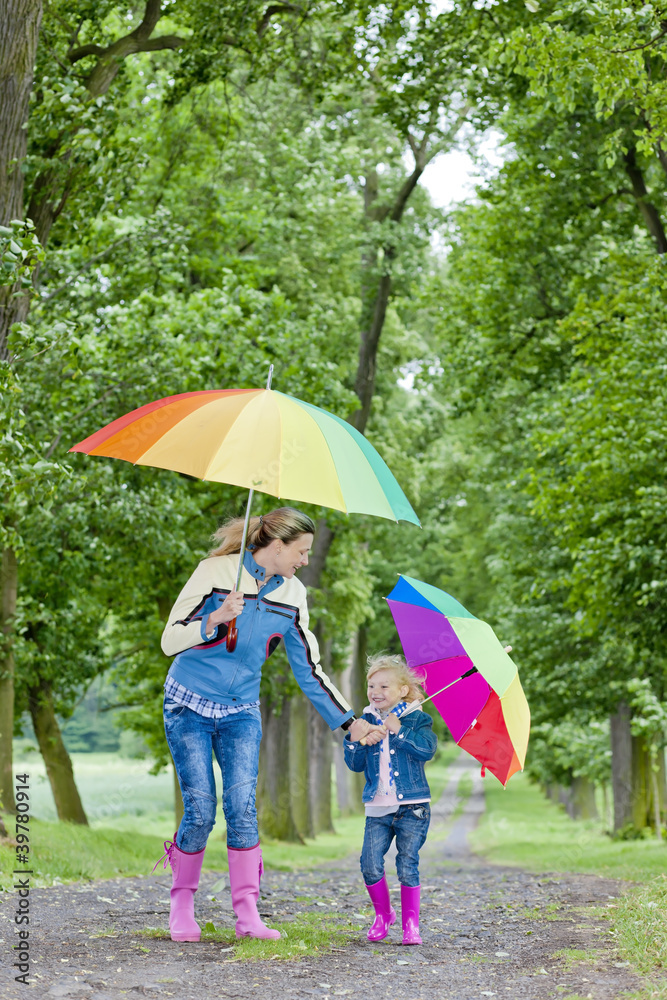 mother and her daughter with umbrellas in spring alley mother and her daughter with umbrellas in spring alley