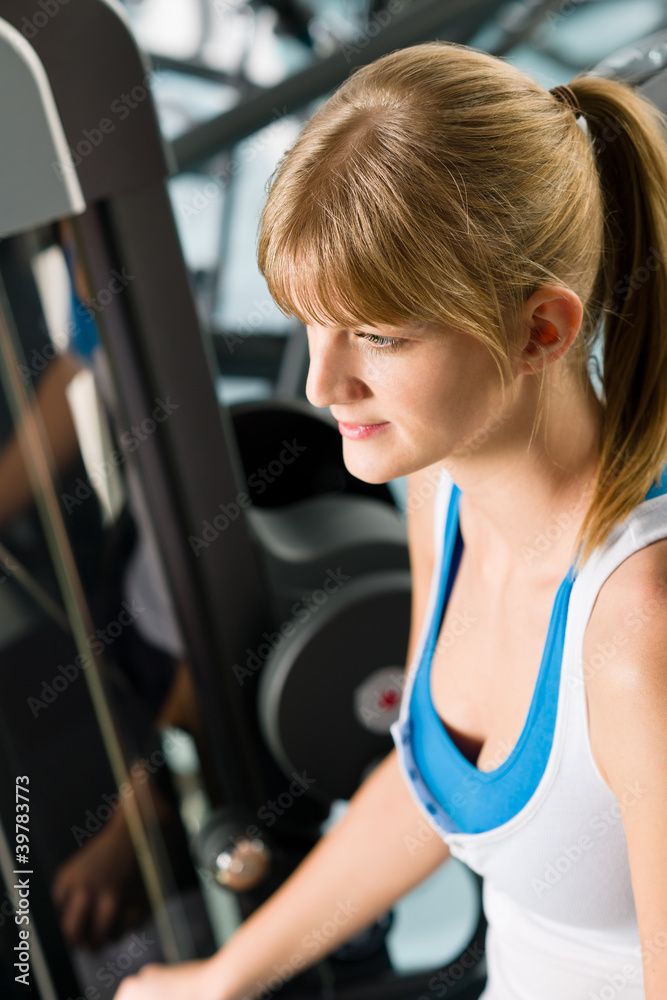 Young woman at fitness center exercise machine Young woman at fitness center exercise machine