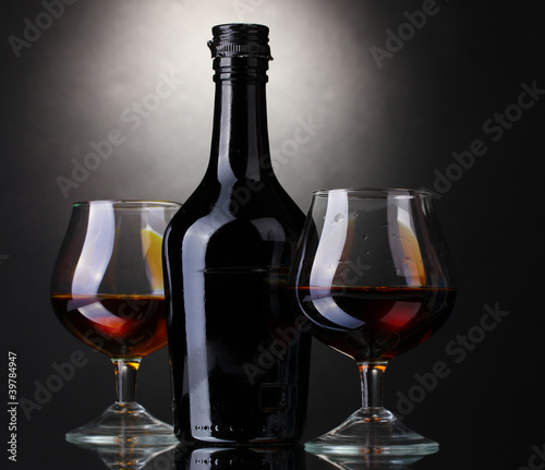 Glasses of brandy and bottle on gray background