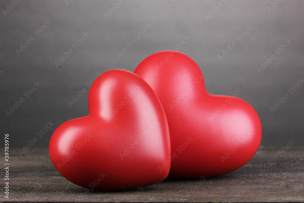 Two decorative red hearts on wooden table on grey background Two decorative red hearts on wooden table on grey background