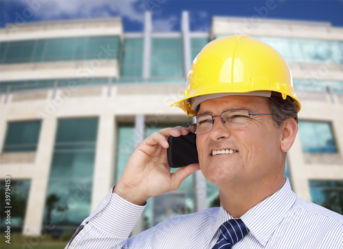 Contractor in Hardhat Talks on Phone In Front of Building