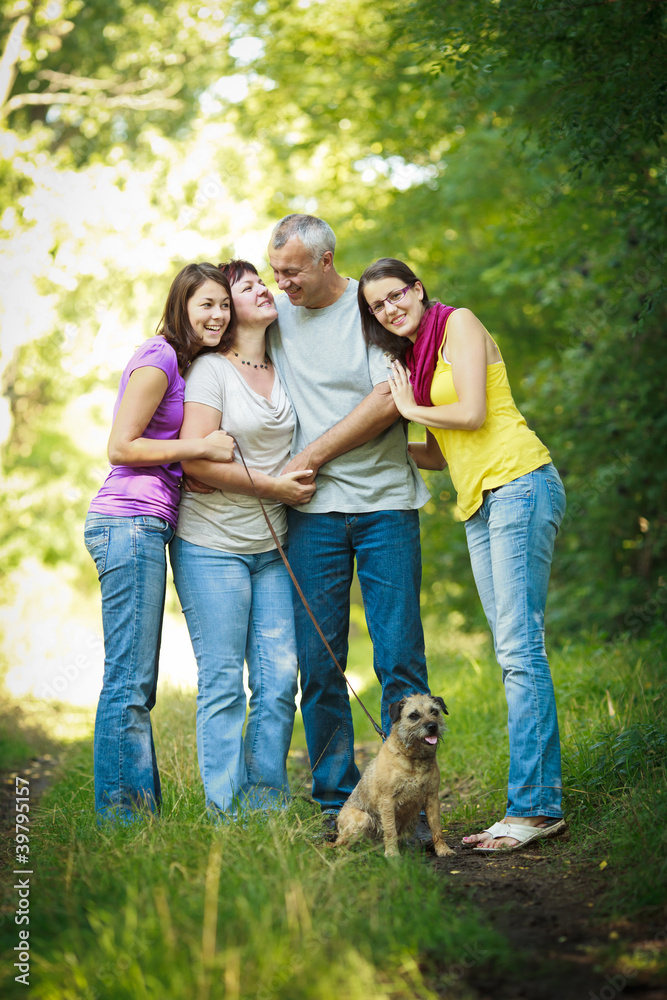 Obraz premium Family portrait - Family of four with a cute dog outdoors