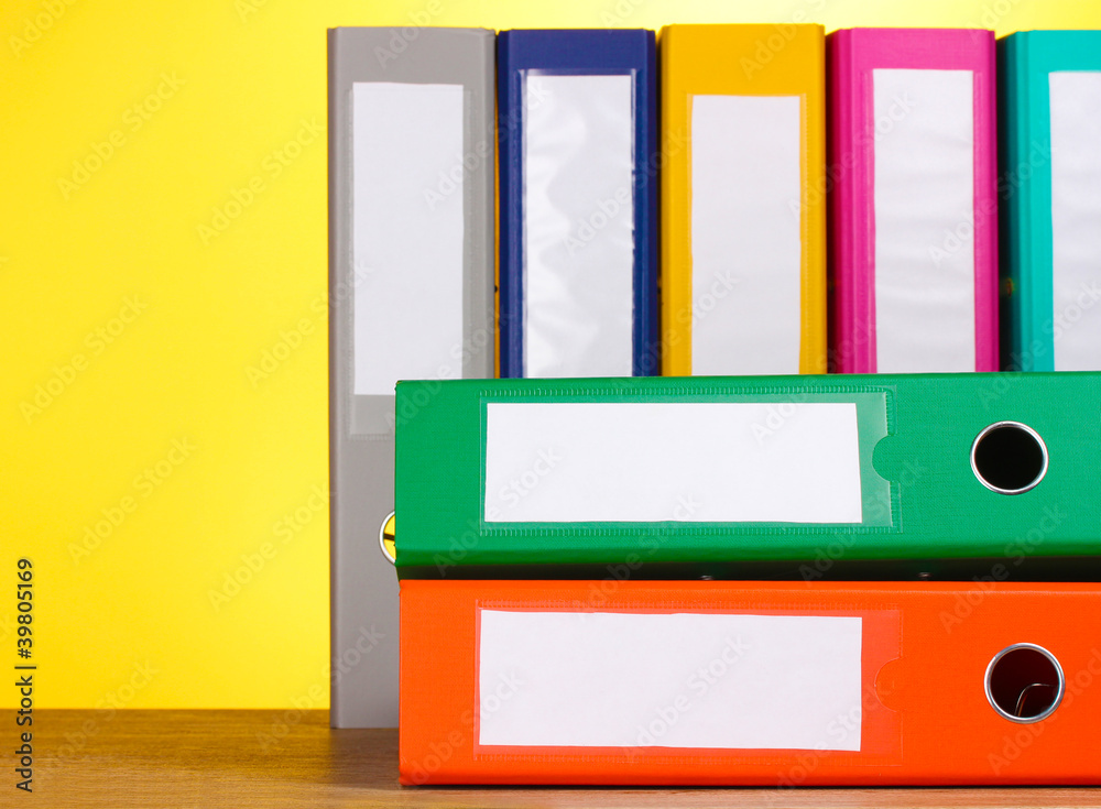 bright office folders on wooden table on yellow background bright office folders on wooden table on yellow background