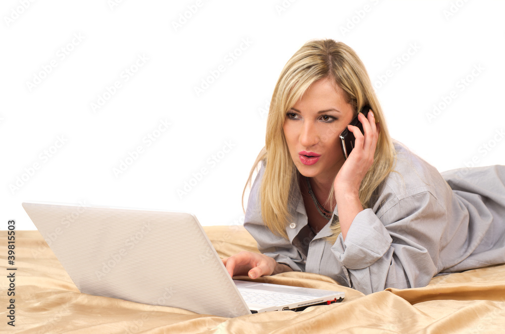 Blonde woman working with laptop on bed Blonde woman working with laptop on bed