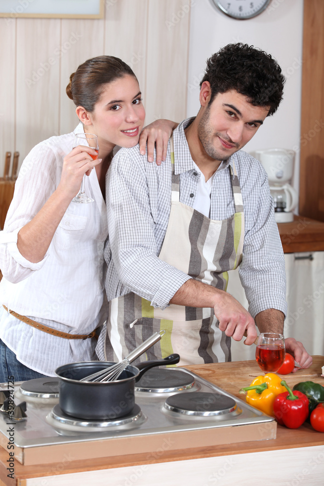 portrait of young man cooking in kitchen with girlfriend portrait of young man cooking in kitchen with girlfriend