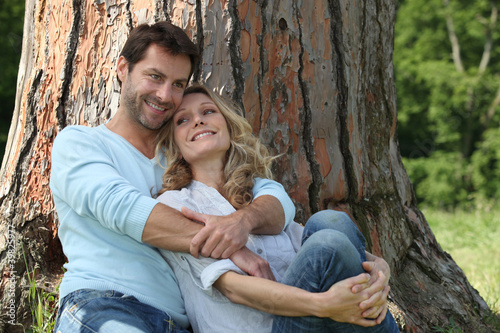Couple sitting against a tree