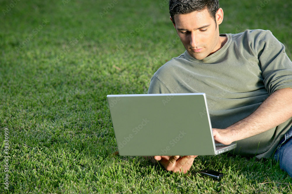 Man relaxing in field with laptop Man relaxing in field with laptop