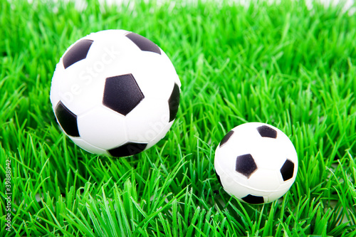 One big and one little soccer ball on plastic grass © Sandra van der Steen