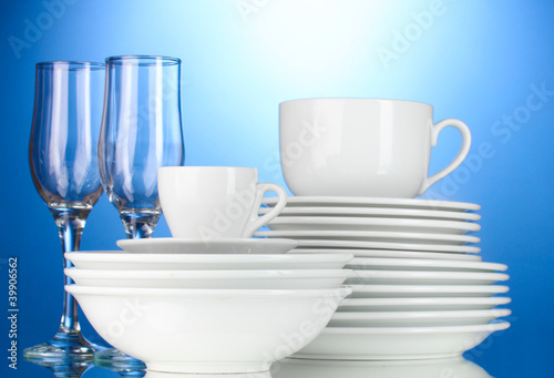 empty bowls, plates, cups and glasses on blue background