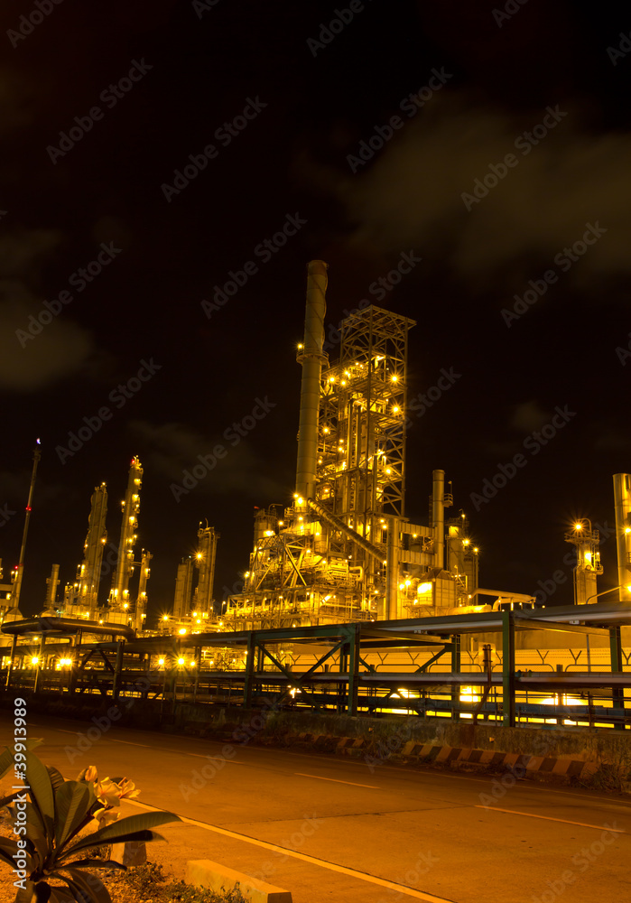 Petrochemical oil refinery plant near a road at night, industria
