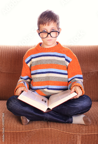 Young child sitting on sofa with book photo