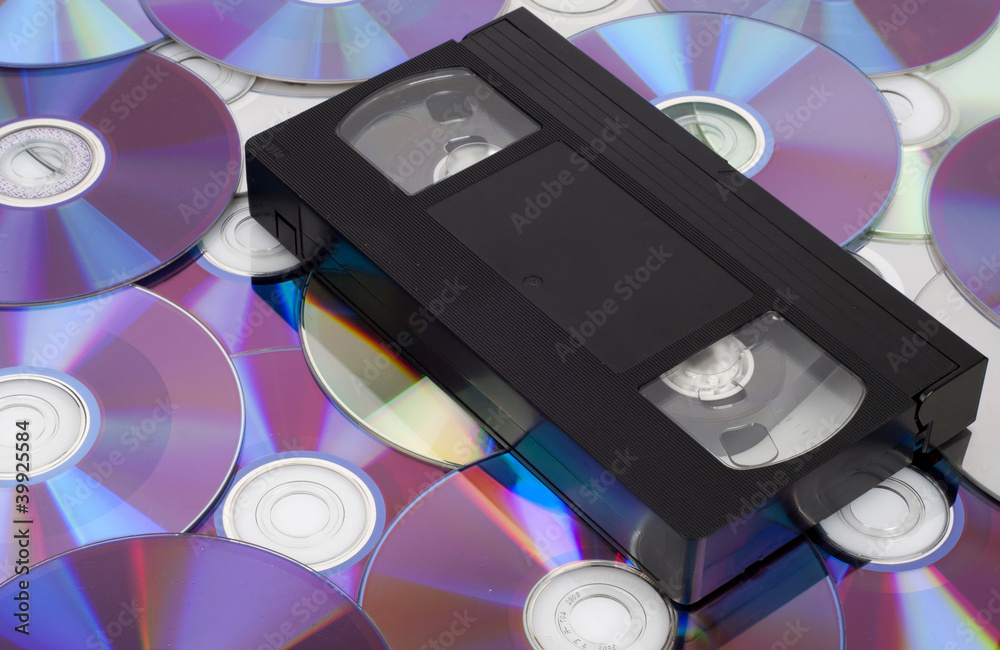 Naklejka premium CD vs VHS. VHS cassette lay on the many CD disks