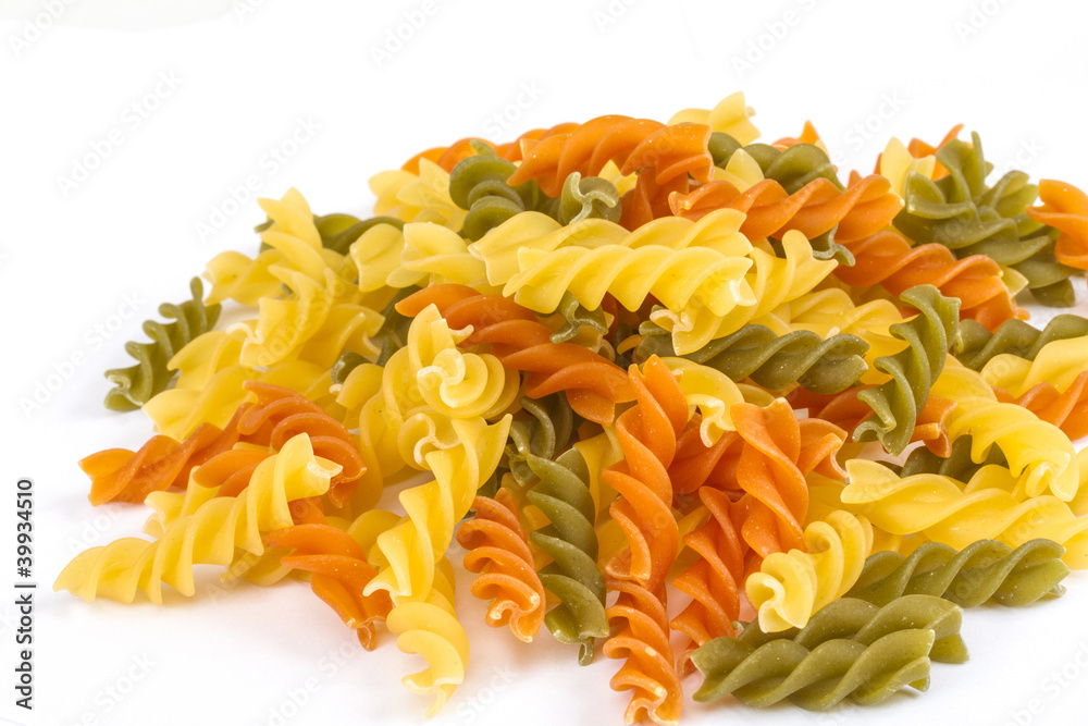 Uncooked pasta fusilli in different colours, white background Uncooked pasta fusilli in different colours, white background
