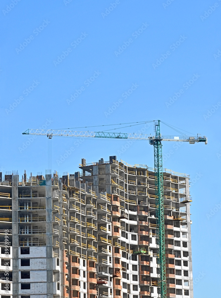 Building crane and building under construction against blue sky