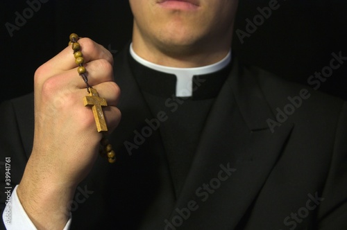 Photo Young Priest praying with rosery in his hands