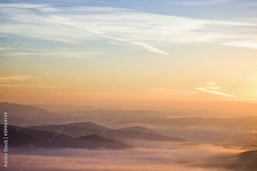 colorful summer morning with golden light and fog between hills