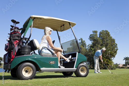 Happy Senior Couple Playing Golf With Cart