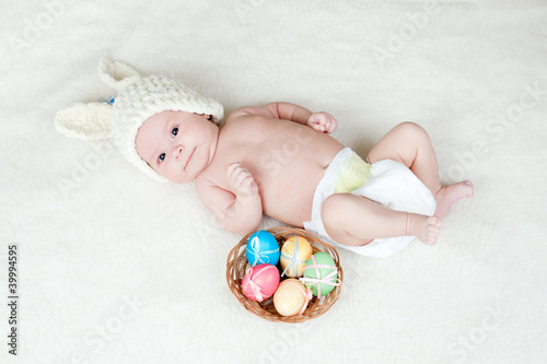adorable baby dressed in Easter bunny cap with eggs in basket