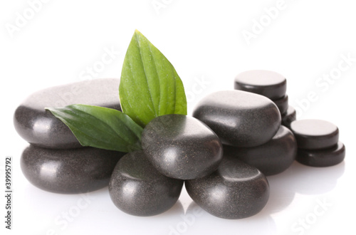 Spa stones and green leaves isolated on white