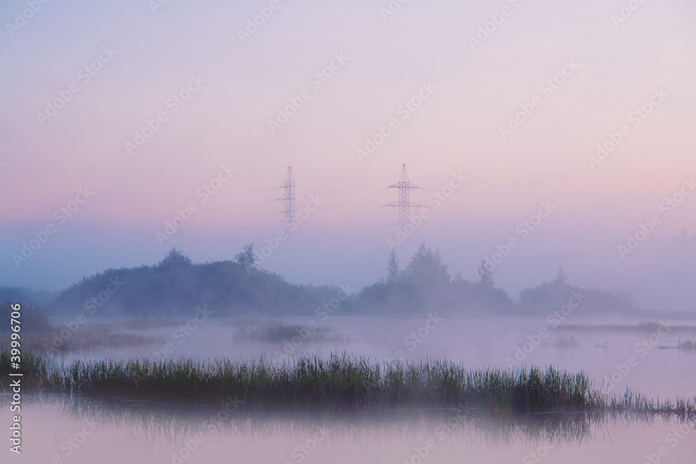 Transmission line on hill which runs through swamp in fog