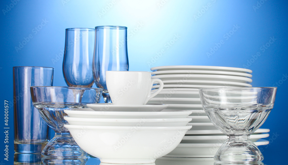 empty bowls, plates, cups and glasses on blue background empty bowls, plates, cups and glasses on blue background