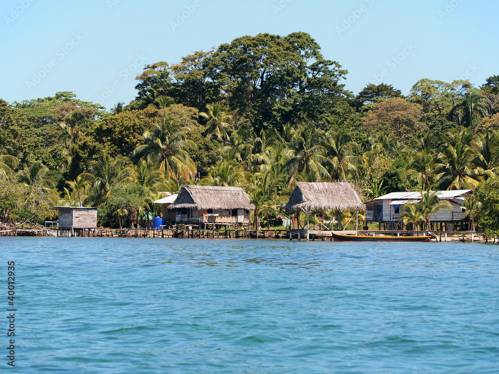 Rustic house with thatched hut over water and lush tropical vegetation on the Caribbean coast, Bocas del Toro, Panama, Central America
