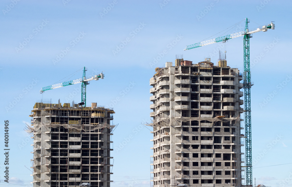 Two Big hoisting tower cranes and construction buildings