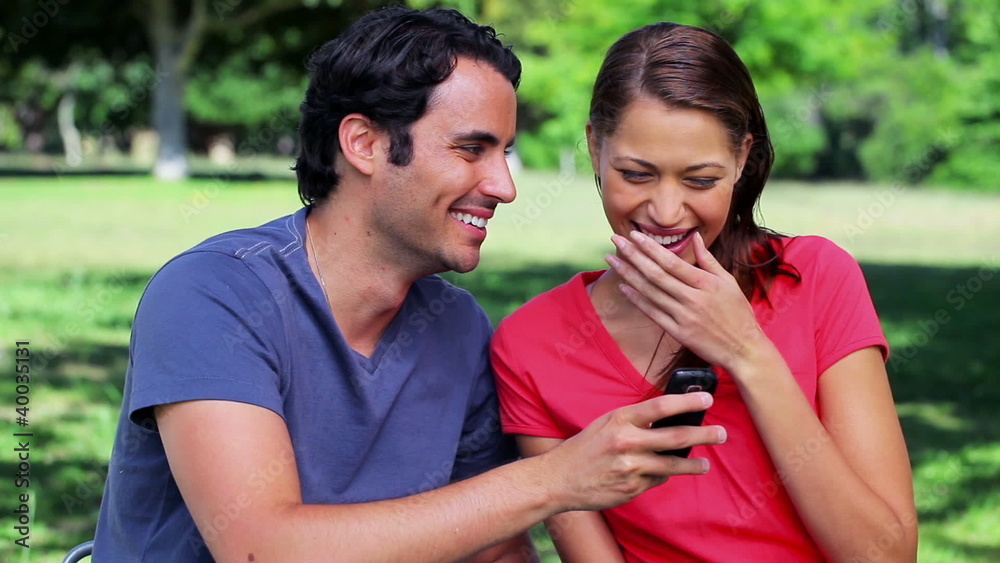 Smiling couple looking at a text on a cellphone Smiling couple looking at a text on a cellphone