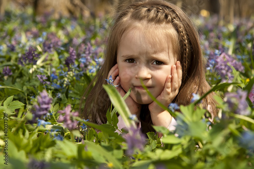 A Girl among colorful flowers in spring forest