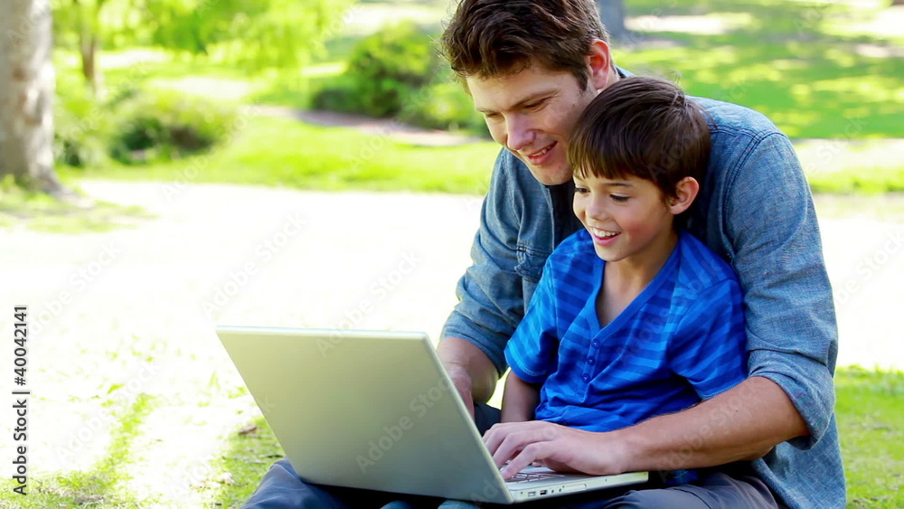 Boy on his father's tigh using a laptop Boy on his father's tigh using a laptop