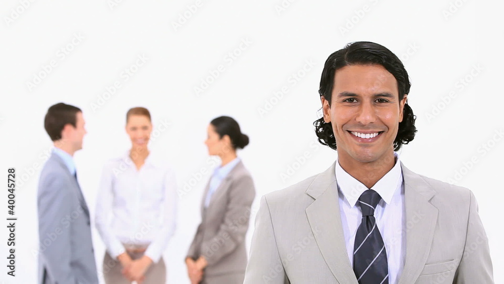 Smiling businessman with colleagues standing behind him Smiling businessman with colleagues standing behind him