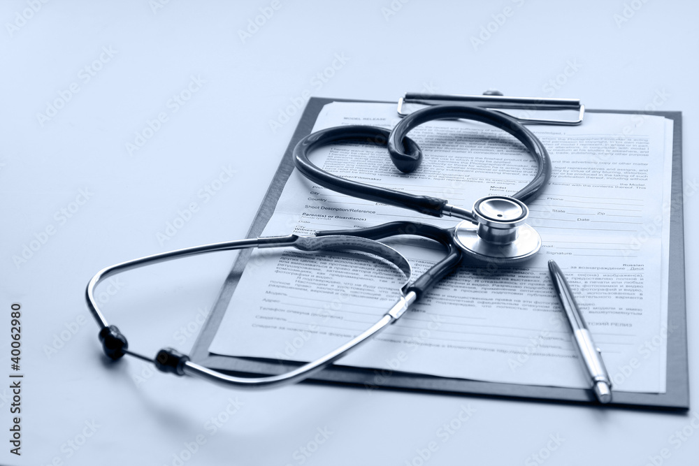 A stethoscope, a pen on a clipboard, isolated on white A stethoscope, a pen on a clipboard, isolated on white